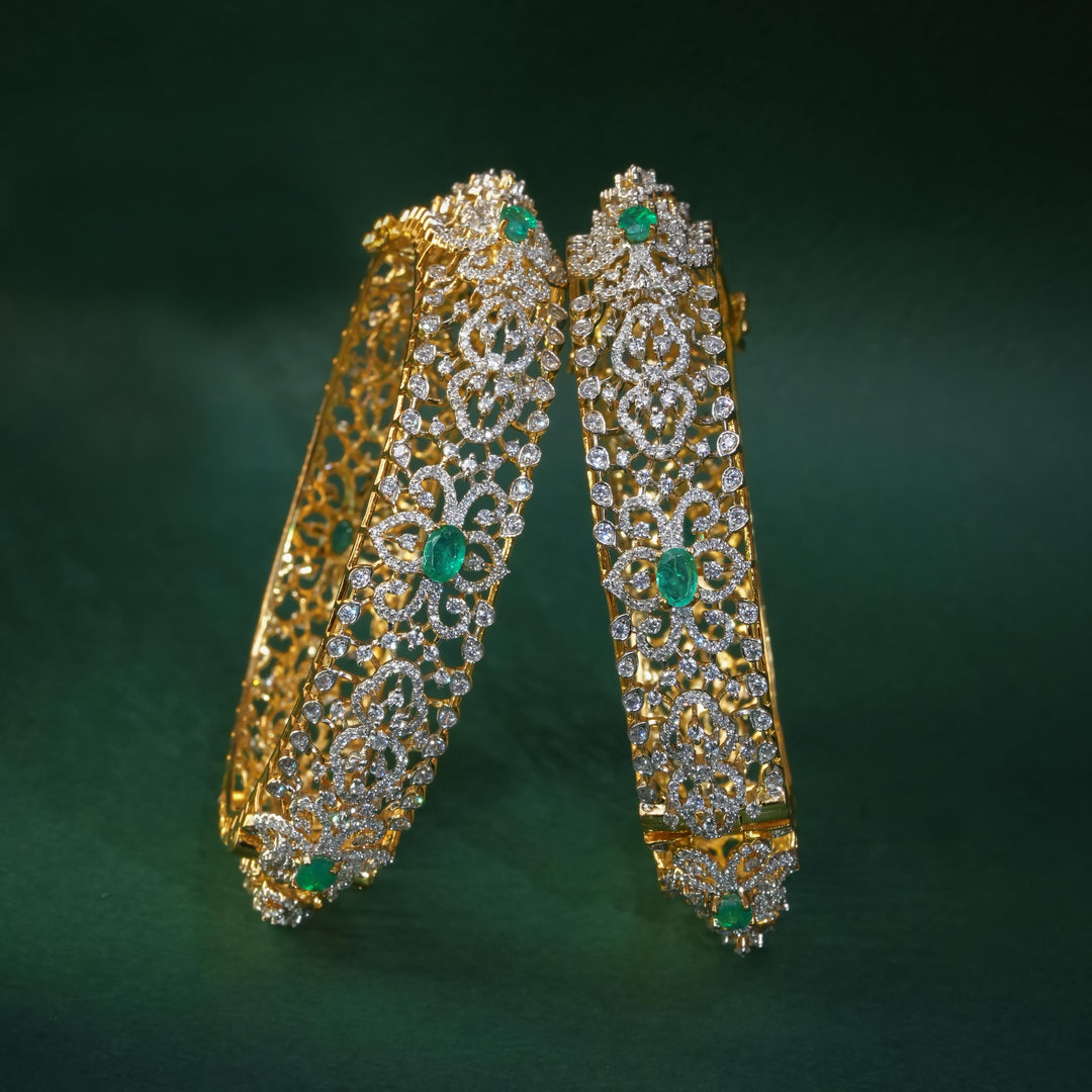 92.5 silver CZ bangles with floral motifs, and semi-precious emerald stones by Sri Fine Jewellery, Hyderabad.
(https://www.srifinejewellery.com)