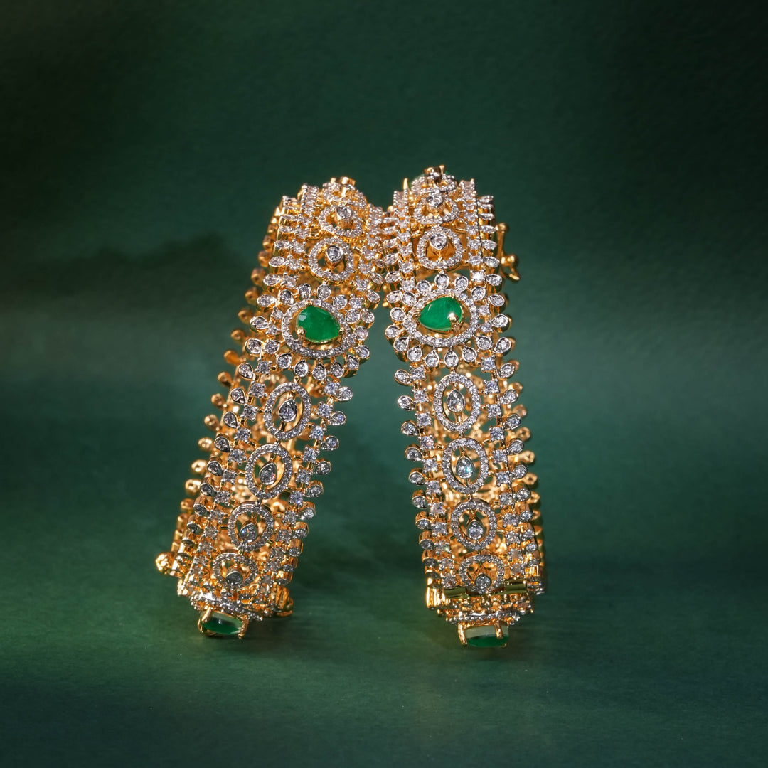 92.5 silver CZ bangles with floral motifs, and semi-precious emerald stones by Sri Fine Jewellery, Hyderabad.
(https://www.srifinejewellery.com)
