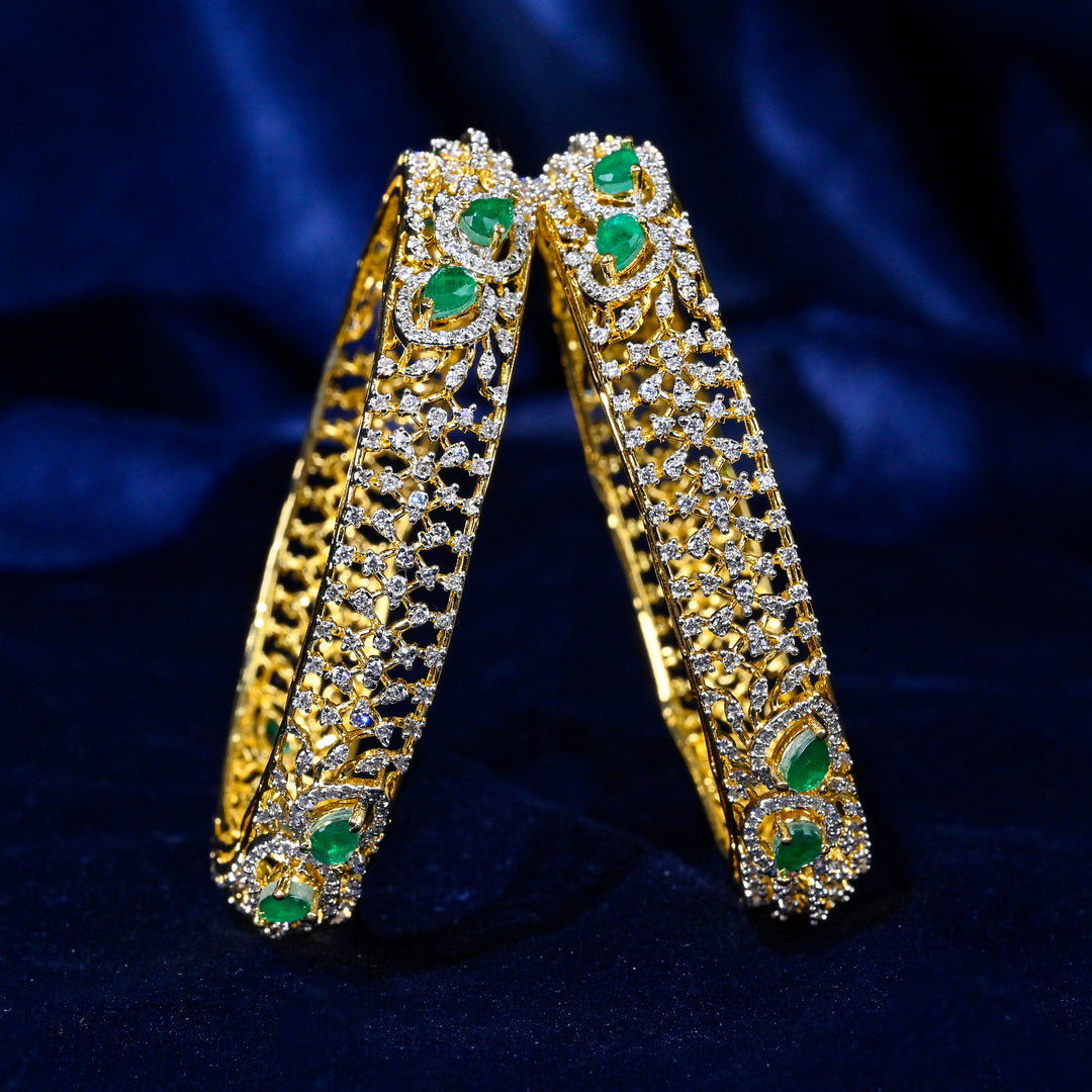 92.5 silver CZ bangles with floral motifs, and semi-precious emerald stones by Sri Fine Jewellery, Hyderabad.
(https://www.srifinejewellery.com)