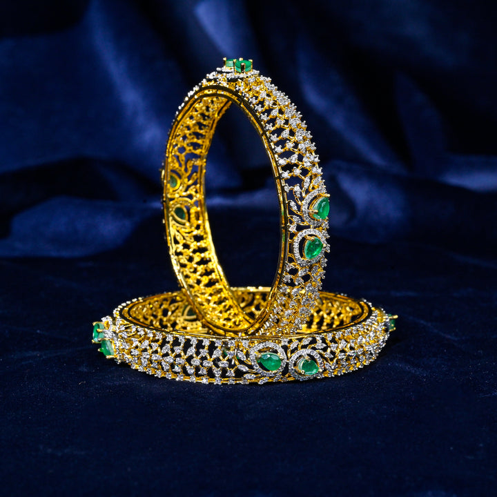 92.5 silver CZ bangles with floral motifs, and semi-precious emerald stones by Sri Fine Jewellery, Hyderabad.
(https://www.srifinejewellery.com)