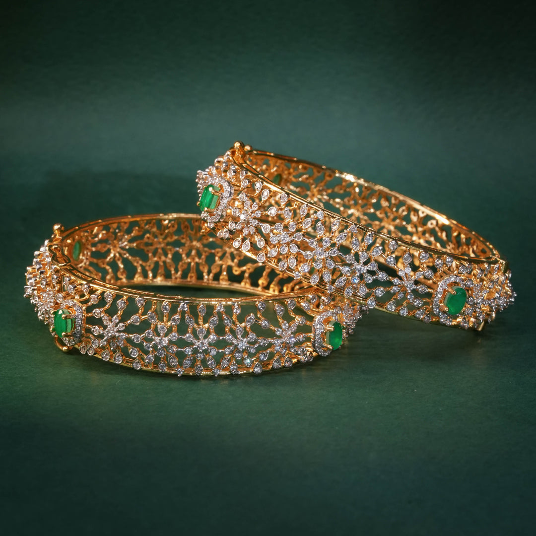 92.5 silver CZ bangles with floral motifs, and semi-precious emerald stones by Sri Fine Jewellery, Hyderabad.
(https://www.srifinejewellery.com)