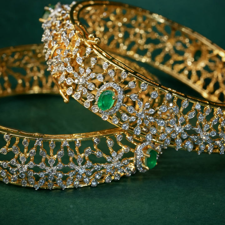 92.5 silver CZ bangles with floral motifs, and semi-precious emerald stones by Sri Fine Jewellery, Hyderabad.
(https://www.srifinejewellery.com)