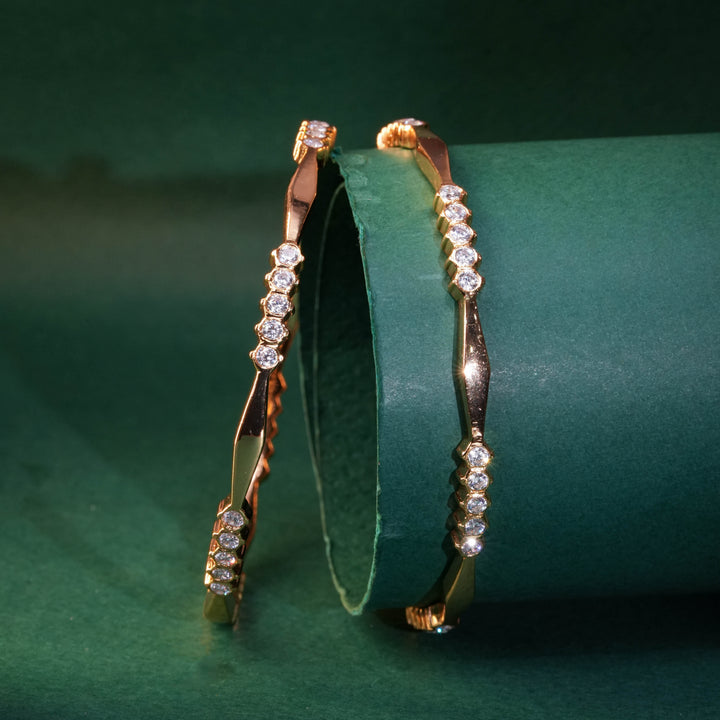 92.5 silver CZ bangles with floral motifs and gold-like finish by Sri Fine Jewellery, Hyderabad.
(https://www.srifinejewellery.com)