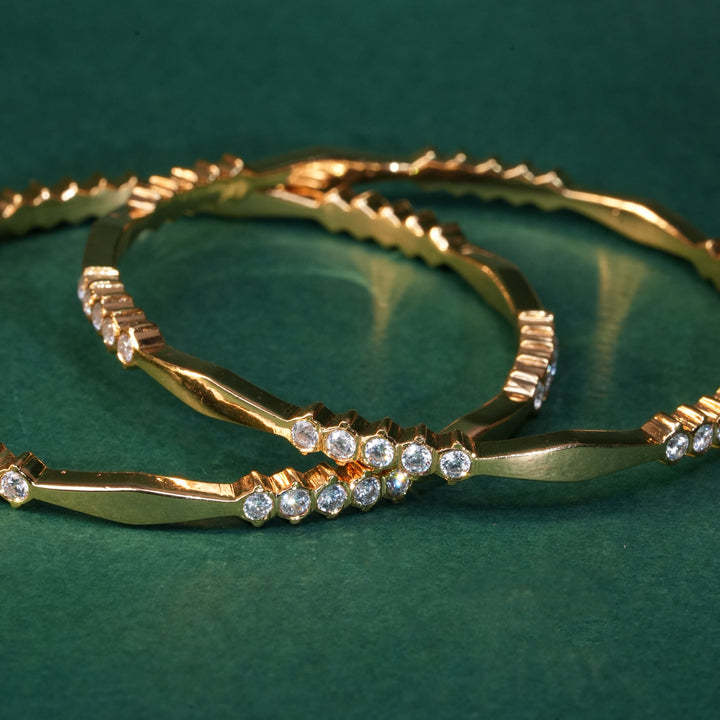 92.5 silver CZ bangles with floral motifs and gold-like finish by Sri Fine Jewellery, Hyderabad.
(https://www.srifinejewellery.com)