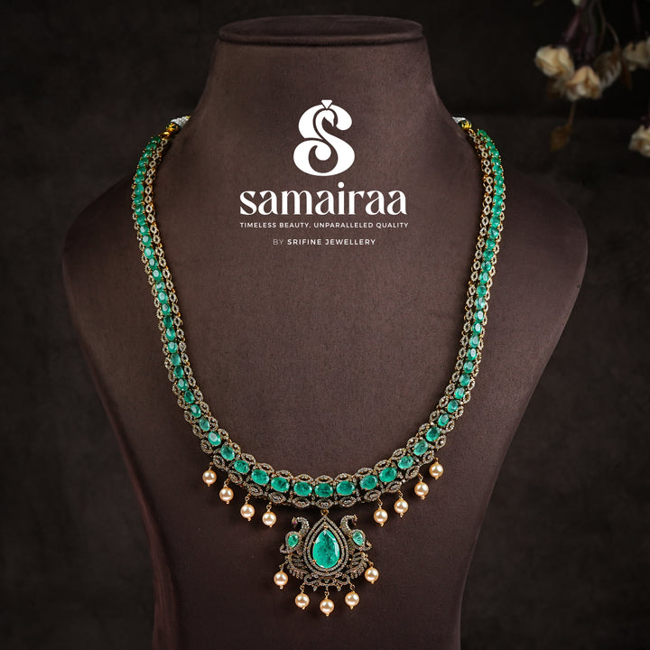 Samairaa emerald green victorian necklace set in 92.5 sterling silver with antique gold finish, pearl hangings and royal bridal design by Sri Fine Jewellery, Hyderabad.
