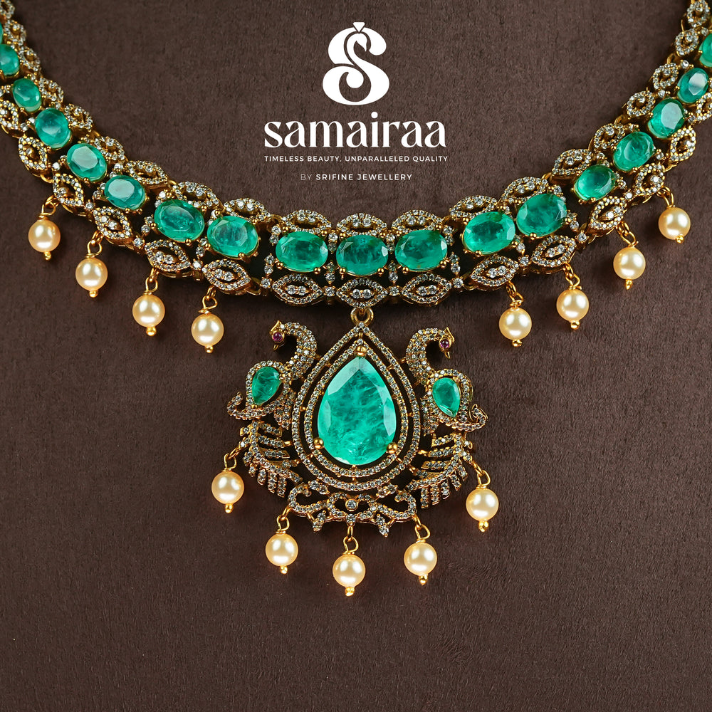 Close-up view of Samairaa emerald green victorian necklace set in 92.5 silver with antique gold finish, pearl hangings and royal bridal design by Sri Fine Jewellery, Hyderabad.