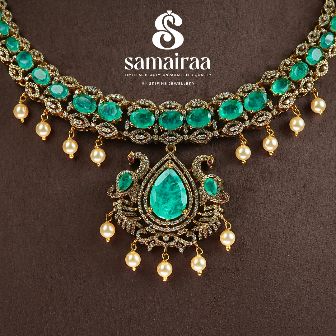 Close-up view of Samairaa emerald green victorian necklace set in 92.5 silver with antique gold finish, pearl hangings and royal bridal design by Sri Fine Jewellery, Hyderabad.