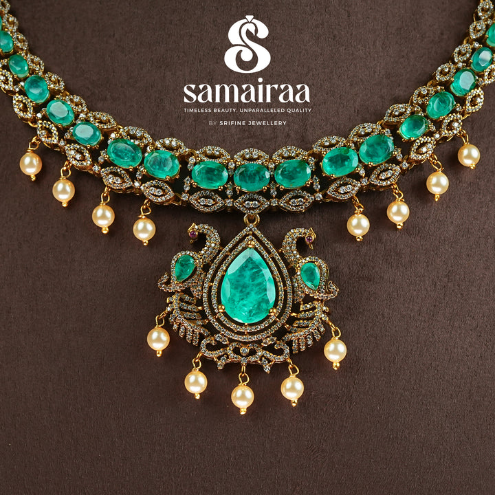 Close-up view of Samairaa emerald green victorian necklace set in 92.5 silver with antique gold finish, pearl hangings and royal bridal design by Sri Fine Jewellery, Hyderabad.