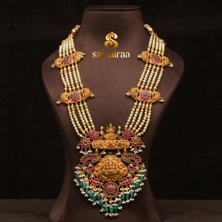 Traditional pearl haram necklace in 92.5 silver with antique gold finish, Lakshmi pendant, kundan stones and green bead drops for South Indian bridal jewellery by Sri Fine Jewellery Hyderabad.
