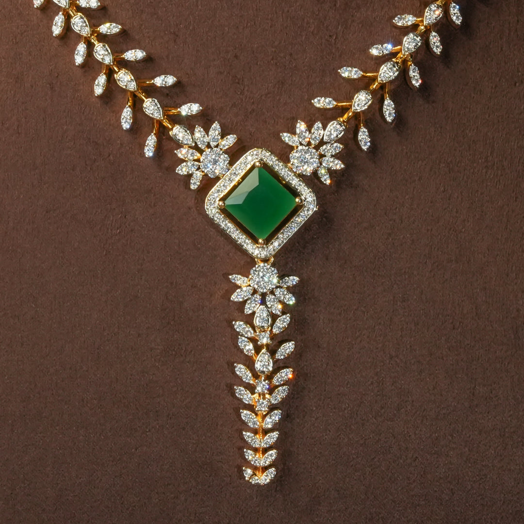 Close-up view of uxury diamond-look silver cz emerald necklace with premium cz stones and semi-precious emerald stone in 92.5 silver, bridal wedding jewellery with gold finish by Sri Fine Jewellery Punjagutta Hyderabad.