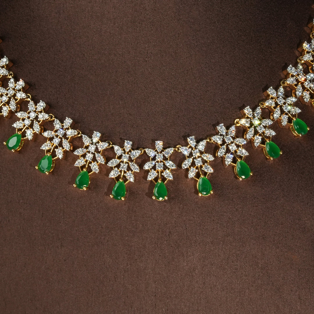 Close-up view of luxury diamond-look silver necklace set with premium cz stones and semi-precious emerald stones in 92.5 silver, bridal wedding jewellery with gold finish by Sri Fine Jewellery Punjagutta Hyderabad.