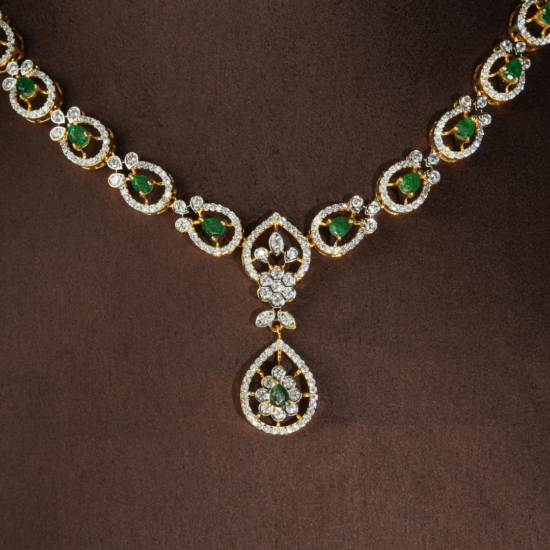 Close-up view of luxury diamond-look silver necklace with premium cz stones and semi-precious emerald stones in 92.5 silver, bridal wedding jewellery with gold finish by Sri Fine Jewellery Punjagutta Hyderabad.