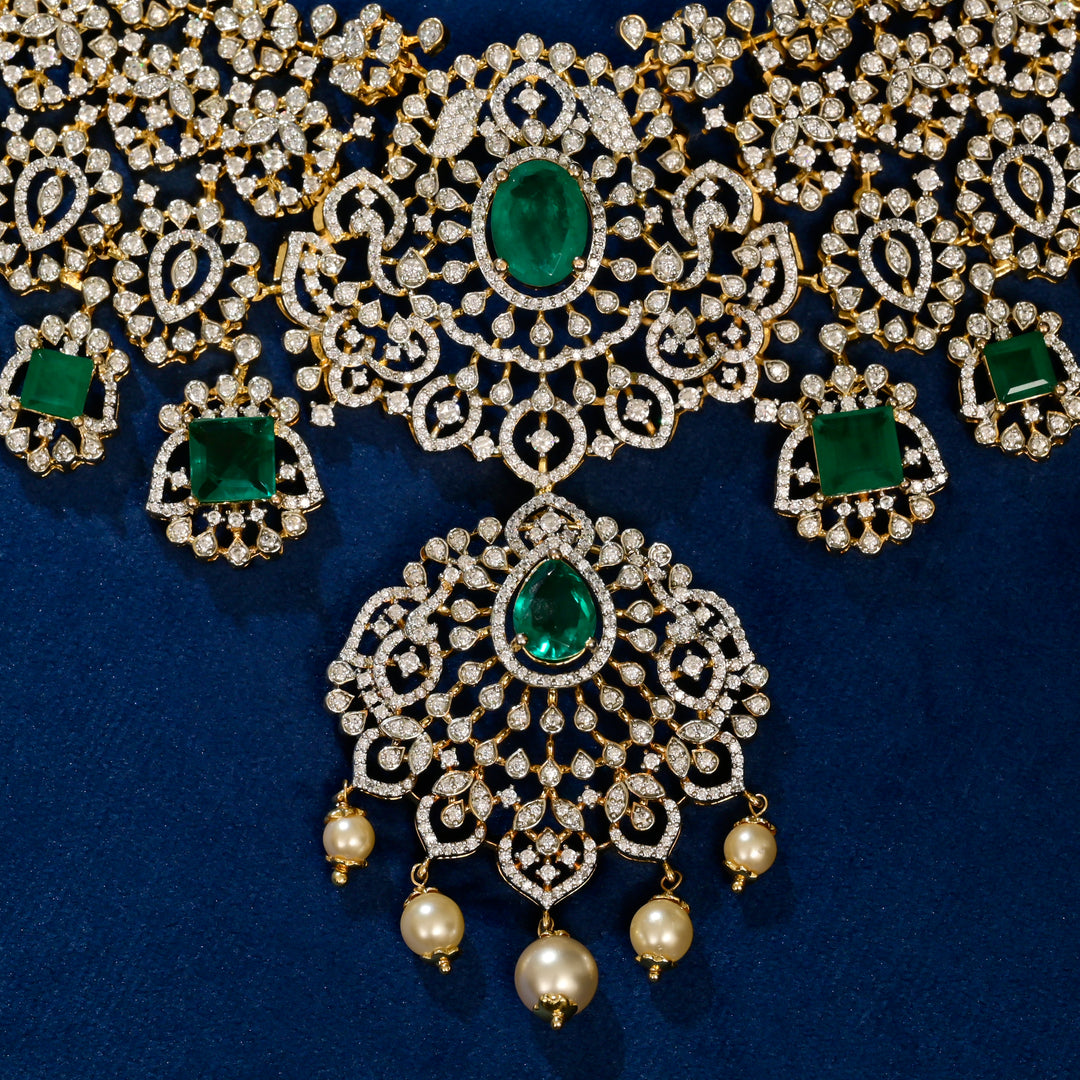Ornate silver necklace with emeralds and pearls on a blue background