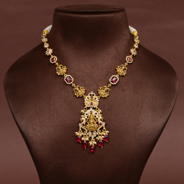 Elegant 92.5 silver temple necklace featuring intricate Lakshmi motif craftsmanship with ruby-toned stones, pearl detailing, and traditional antique gold finish. Handcrafted designer necklace with premium cz embellishments, perfect for bridal wear, festive occasions, weddings, and traditional ethnic styling.
Sri Fine Jewellery, Hyderabad 