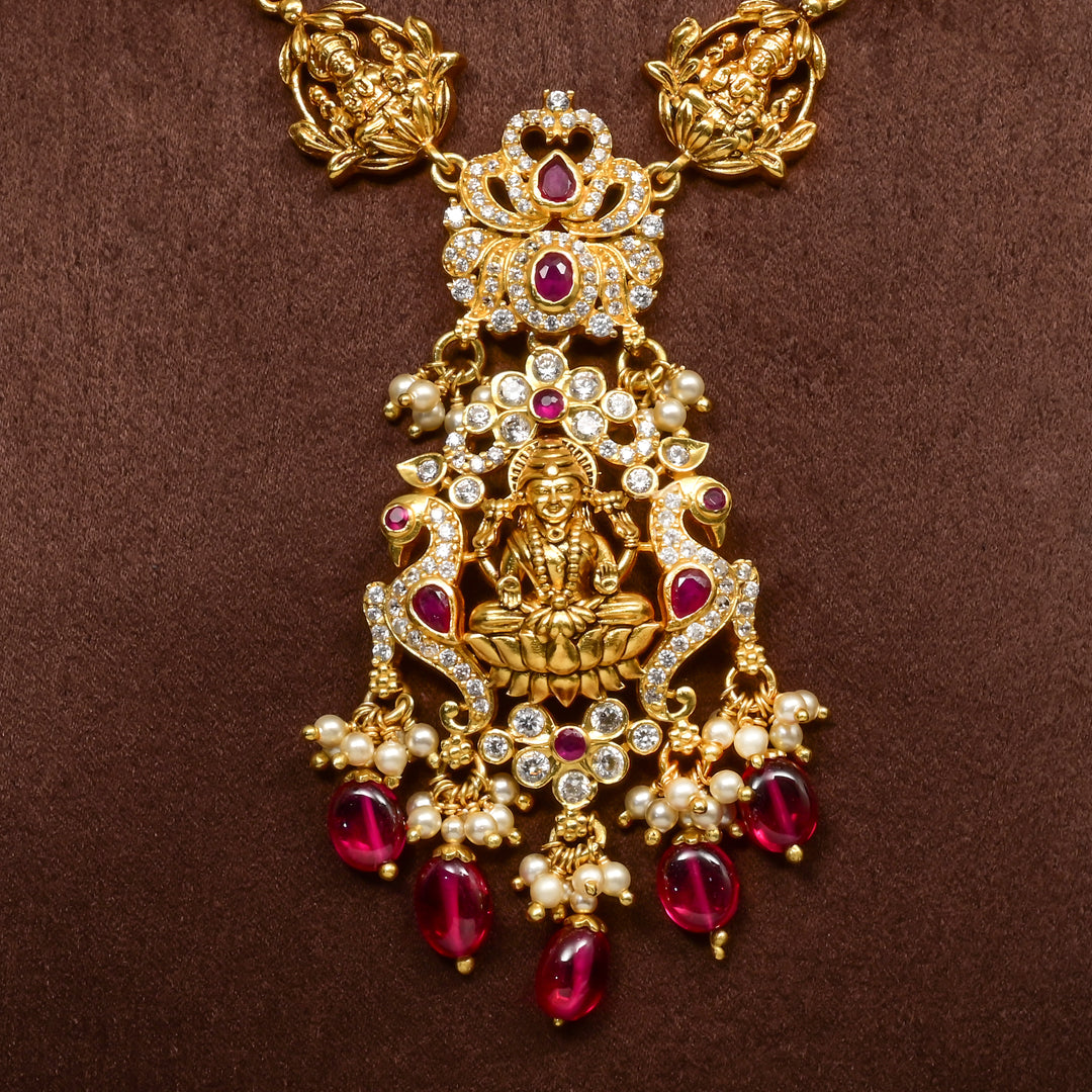 Close-up view of elegant 92.5 silver temple necklace featuring intricate Lakshmi motif craftsmanship with ruby-toned stones, pearl detailing, and traditional antique gold finish. 
Sri Fine Jewellery, Hyderabad