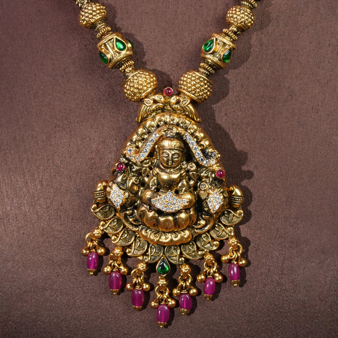 Close-up view of 92.5 sterling silver temple necklace with Lakshmi pendant, cz stone accents, antique gold finish, and traditional South Indian bridal jewellery design by Sri Fine Jewellery Hyderabad.
