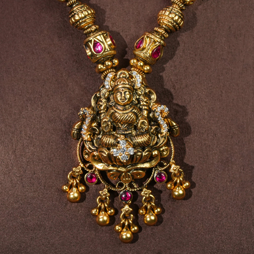 Close-up view of 92.5 sterling silver temple choker necklace with Lakshmi pendant, ruby stone accents, antique gold finish, and traditional South Indian bridal jewellery design by Sri Fine Jewellery Hyderabad.
