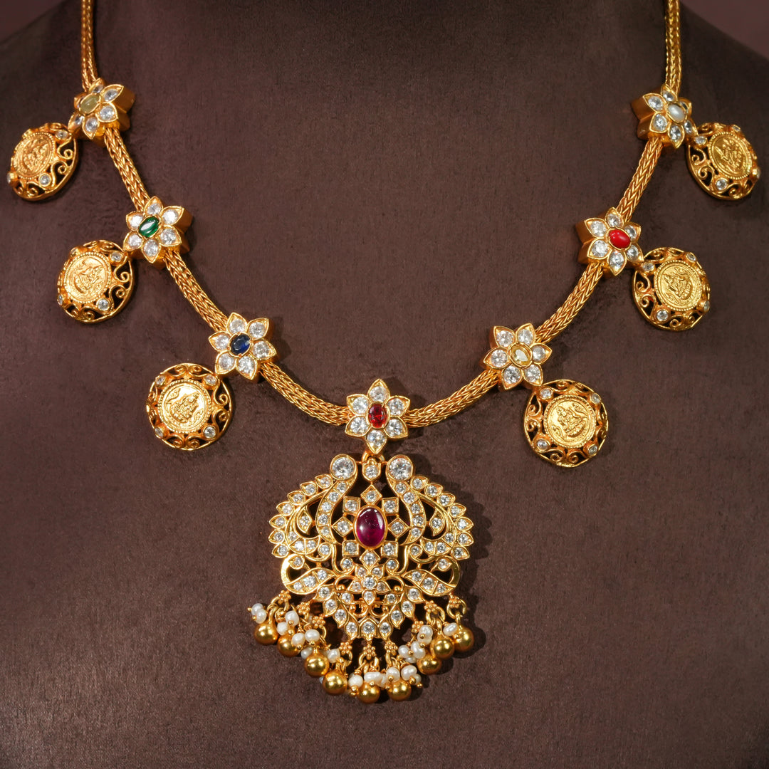 92.5 sterling silver floral necklace with antique coin motifs, ruby stone centerpiece, cz detailing, and traditional South Indian bridal pendant in premium gold finish by Sri Fine Jewellery Hyderabad.
