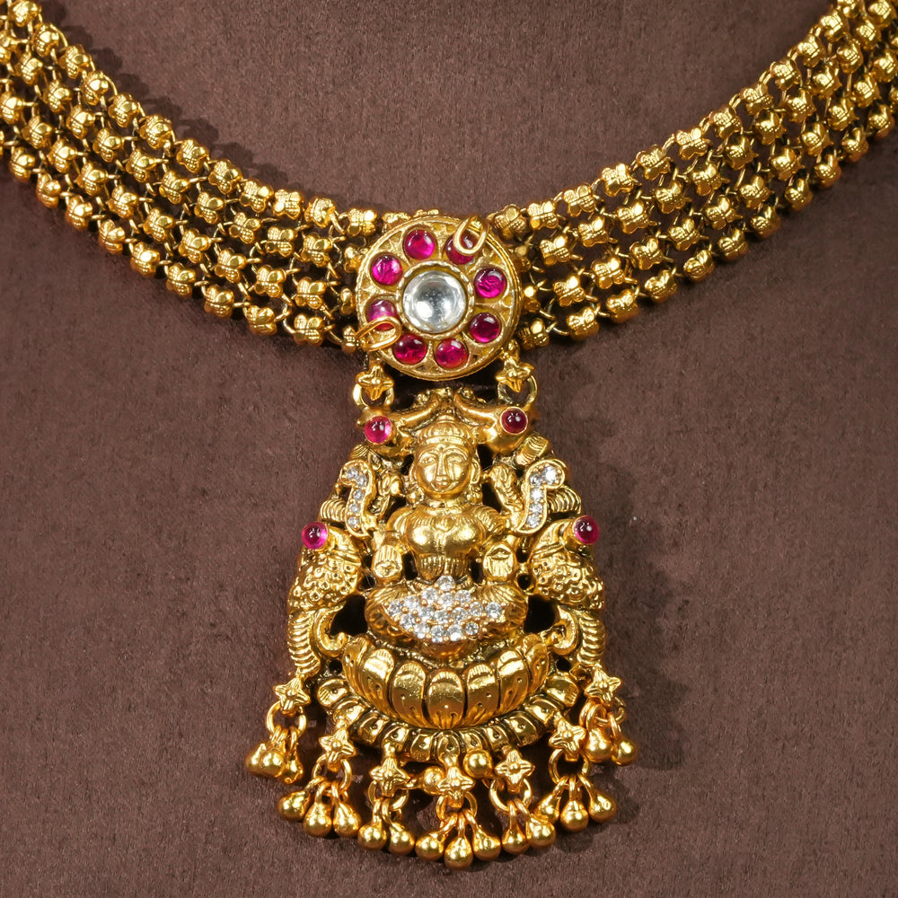 Close-up view of 92.5 sterling silver temple choker necklace with Lakshmi pendant, ruby stone accents, antique gold finish, and traditional South Indian bridal jewellery design by Sri Fine Jewellery Hyderabad.
(https://srifinejewellery.com)