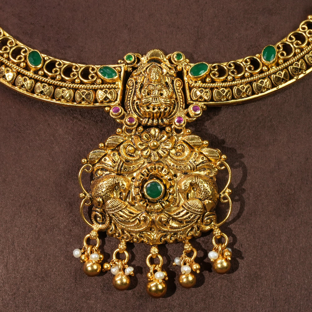 Close-up view of antique Lakshmi temple necklace in 92.5 sterling silver with gold finish, green stone detailing, handcrafted South Indian bridal jewellery and traditional heritage pendant design by Sri Fine Jewellery Hyderabad.
