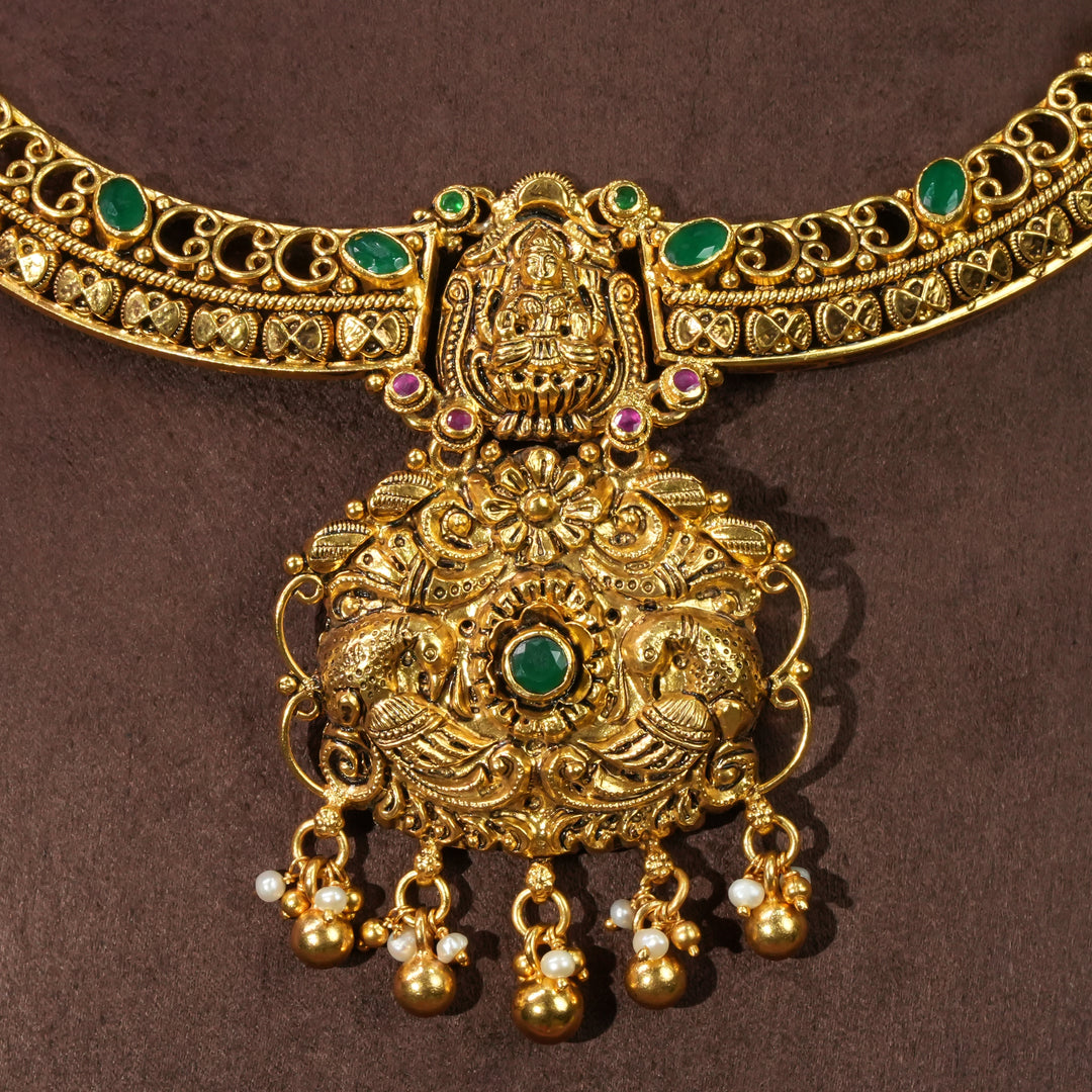Close-up view of antique Lakshmi temple necklace in 92.5 sterling silver with gold finish, green stone detailing, handcrafted South Indian bridal jewellery and traditional heritage pendant design by Sri Fine Jewellery Hyderabad.
