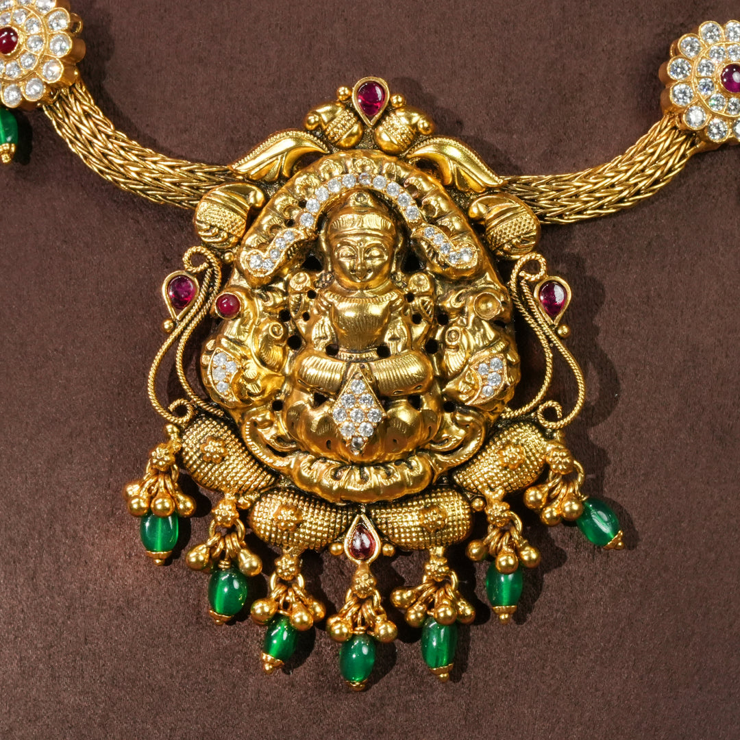 Close-up view of traditional Lakshmi temple necklace in 92.5 silver with antique gold finish, cz stone detailing, green bead drops and handcrafted South Indian bridal jewellery design by Sri Fine Jewellery Hyderabad.
(https://srifinejewellery.com)